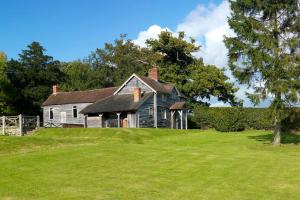 an old house on a green field with a tree at Spacious Holiday Cottage with Scenic Views in Church Stretton