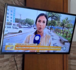 un écran de télévision avec une femme tenant un microphone dans l'établissement Cantinho da Paz, à Niterói