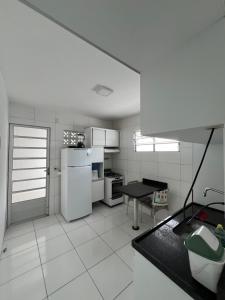 uma cozinha branca com um frigorífico e uma mesa em Nox Temporada - Casa com Piscina e Churrasqueira em Caruaru
