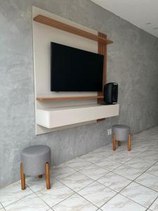 uma sala de estar com dois bancos e uma televisão na parede em Nox Temporada - Casa com Piscina e Churrasqueira em Caruaru
