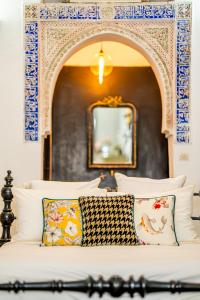a bed with blue and white pillows and a mirror at Riad Tibibt in Marrakesh