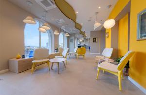 a waiting room with yellow and white chairs and tables at Bluesun Hotel Jadran in Tučepi