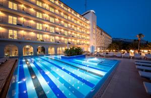 uma piscina em frente a um hotel à noite em Bluesun Hotel Jadran em Tučepi