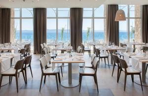 restauracja ze stołami, krzesłami i oknami w obiekcie Bluesun Hotel Jadran w Tučepi