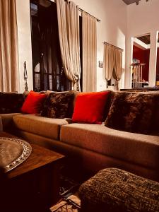 uma sala de estar com um sofá castanho com almofadas vermelhas em Villa Septha em Marrakech