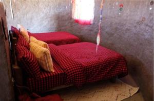 Habitación con 2 camas y manta roja y blanca a cuadros. en Mombo Maasai Culture Homestay, 