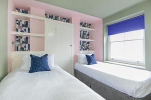 two beds in a room with pink and blue at Harbour Court - Free Parking - tucked away on the Barbican - by Ocean City Retreats in Plymouth