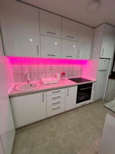 een keuken met een wastafel en roze verlichting bij Apartman Lana in Pale