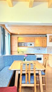 cocina con mesa de madera y sofá azul en Apartments Amelie Kaunerberg -1-, en Kaunerberg