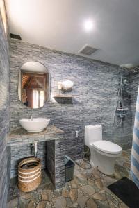 a bathroom with a sink and a toilet and a mirror at Matapalo Bungalows Uluwatu in Uluwatu