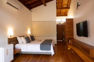 a bedroom with a bed and a flat screen tv at Tiradentes Boutique Hotel in Tiradentes