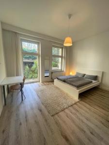 a bedroom with a bed and a desk and windows at Altbauwohnung mit 2 Balkonen in Wuppertal