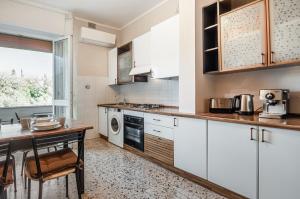 une cuisine avec des placards blancs et une table dans l'établissement Sailing Ships Cozy flat x5 with balcony, à La Spezia