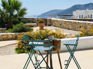 a patio with two chairs and a table and flowers at VILLA THEIA - SELENE , appartement de charme pour 4 à 6 personnes prés de la plage et du village de Koufonissi in Koufonisia