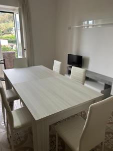 une table à manger avec des chaises blanches et une télévision dans l'établissement Solymar House Lacco Ameno, à Ischia