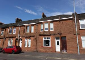 a red car parked in front of a brick building at Mossend Apartment by Klass Living Bellshill in Mossend