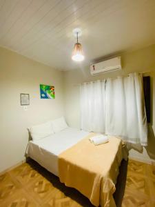 um quarto com uma cama branca e uma janela em Caraiva Hostel em Caraíva