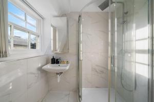 a white bathroom with a shower and a sink at The Signature Residences in London