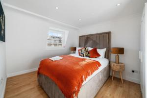 um quarto com uma cama grande e um cobertor laranja em The Signature Residences em Londres