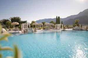 ein großer Pool mit Stühlen und Sonnenschirmen in der Unterkunft Weinegg Wellviva Resort in Appiano sulla Strada del Vino