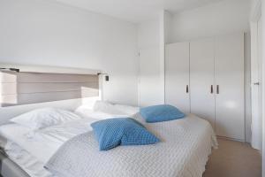 a white bed with two blue pillows on it at Studio Deluxe 2 Pers Punt West - Land view - Ouddorp in Ouddorp