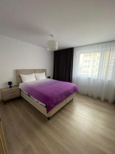 - une chambre avec un lit et une couverture violette dans l'établissement Urban Alexa Home, à Braşov