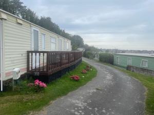 a house with a deck and flowers on the side of a road at Caravan F8 Aberystwyth Holiday Village in Aberystwyth