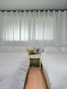 Un dormitorio con dos camas y una mesa con lámpara. en macity, en Incheon