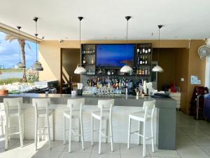 a bar in a restaurant with white stools at Casa Azure Aruba in Palm-Eagle Beach