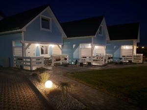 une maison blanche avec terrasse couverte la nuit dans l'établissement Comfortable holiday homes for 8 people, Niechorze, à Niechorze