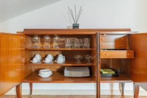 a wooden cabinet with plates and glasses and dishes at Loft Glicine, by R Collection apartment in Brienno