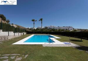 una piscina en un patio con palmeras en APARTAMENTO TREBUJENA, en Conil de la Frontera