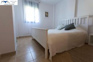 1 dormitorio con cama blanca y ventana en APARTAMENTO TREBUJENA, en Conil de la Frontera