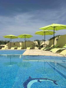 una piscina con sombrillas y sillas verdes en Maison Blum, en Saint-Laurent-des-Arbres