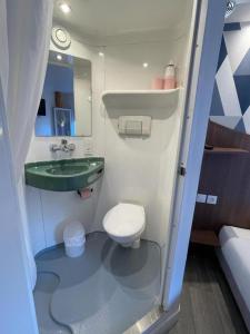 a small bathroom with a toilet and a sink at Kyriad Direct Val de Reuil in Val de Reuil