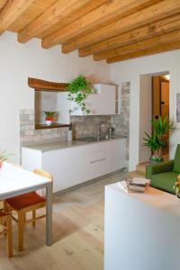 a kitchen with white cabinets and a table and chairs at Residence Porta Della Muda in Vittorio Veneto