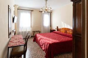 a bedroom with a red bed and a table and a window at Hotel Tivoli in Venice