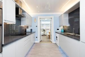 a kitchen with white cabinets and black counter tops at ALTIDO Beautiful 3bed house with Garden and Parking in Pitlochry