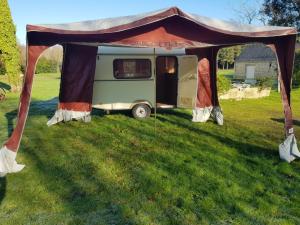 a caravan under a tent in a field at La Eriba Puck in Nort-sur-Erdre +4 photos