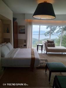1 dormitorio con cama, sofá y ventana grande en Dondi's Way - a private vacation home in the heart of Tagaytay City, en Tagaytay