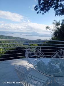 una mesa de cristal y sillas en un balcón con vistas en Dondi's Way - a private vacation home in the heart of Tagaytay City, en Tagaytay