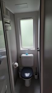 een kleine badkamer met een toilet en een raam bij Modern 6P Tiny SolHouse 6 - Near Groningen in Kropswolde