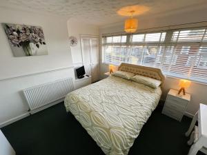 a bedroom with a bed and a tv and windows at Ivy Garden in Sandown