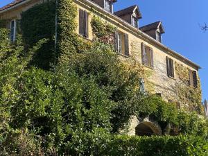 um velho edifício de tijolos com hera a crescer nele em Le Manoir De St Marcel em Saint-Marcel-du-Périgord
