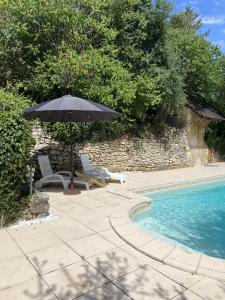 an umbrella and chairs next to a swimming pool at Le Manoir De St Marcel in Saint-Marcel-du-Périgord