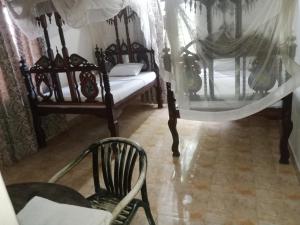 a room with a bed and a chair and a mirror at Paradise House in Lamu