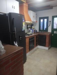 a kitchen with a black refrigerator and a brick wall at House prado in Barranquilla