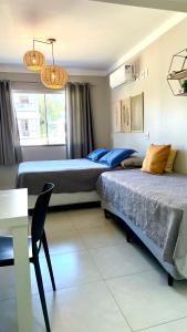 2 camas en una habitación con mesa y escritorio en Residencial Rumo ao Mar - Bombinhas-SC, en Bombinhas