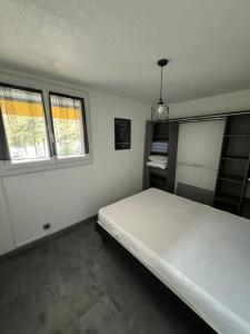een slaapkamer met een wit bed en 2 ramen bij Appartement T2 cap d agde au calme proche toute commodité port et île des loisirs in Cap d'Agde