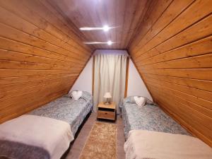 two twin beds in a room with wood paneling at Chalé Zimbro, Serra da Estrela, Penhas da Saúde in Penhas da Saúde